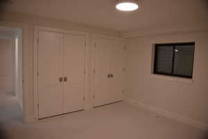 Unfurnished bedroom featuring light colored carpet and multiple closets