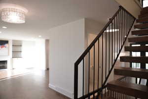 Stairs with built in features, a fireplace, wood finished floors, and recessed lighting
