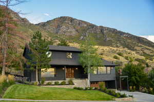 View of front of home featuring a front yard, a mountain view, concrete driveway, and brick siding