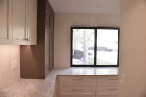 Kitchen with white cabinetry and light stone countertops