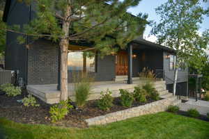 Back of house featuring brick siding and covered porch