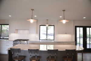 Kitchen with white cabinetry, a center island, stainless steel gas stove, pendant lighting, and recessed lighting