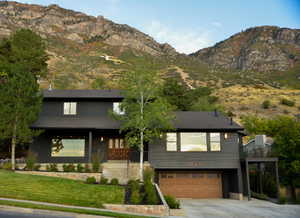 View of front of property with a mountain view, concrete driveway, a garage, a front yard, and a porch