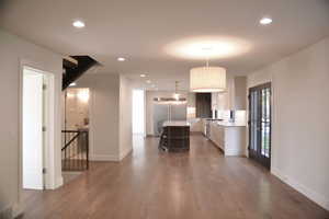 Kitchen featuring white cabinets, recessed lighting, hanging light fixtures, stainless steel built in fridge, and a center island