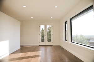 Spare room featuring french doors, recessed lighting, plenty of natural light, and wood finished floors
