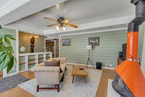 Living area with wood finished floors, a ceiling fan, and wooden walls