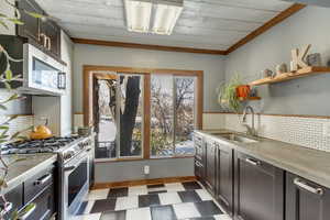 Kitchen featuring dark floors, gas stove, tasteful backsplash, dark brown cabinetry, and open shelves