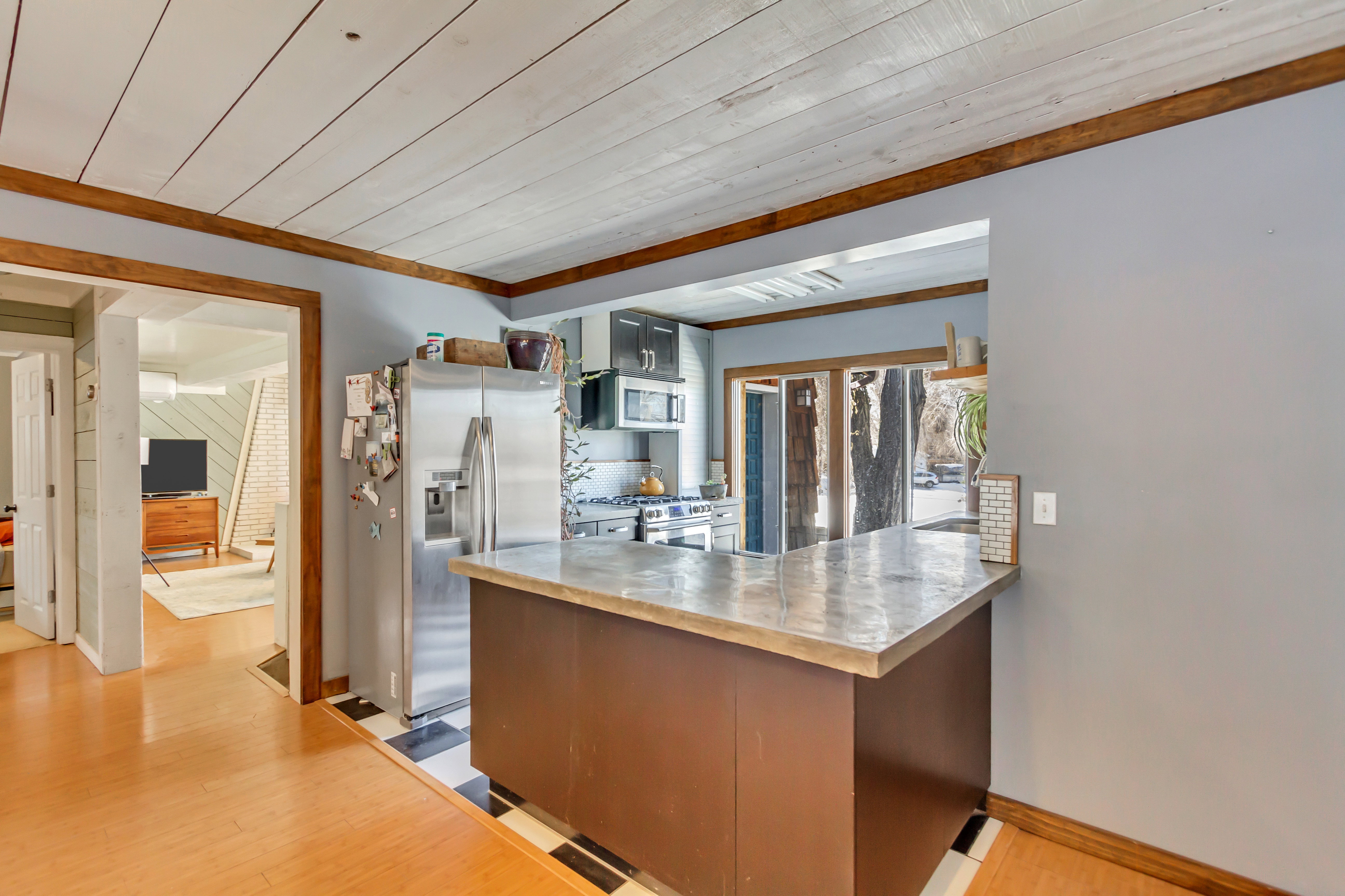 Kitchen featuring stainless steel appliances, a peninsula, light wood finished floors, light countertops, and wooden ceiling