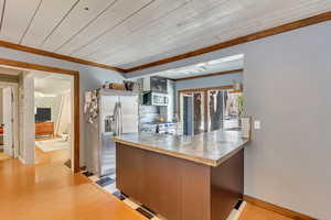 Kitchen featuring stainless steel appliances, a peninsula, light wood finished floors, light countertops, and wooden ceiling