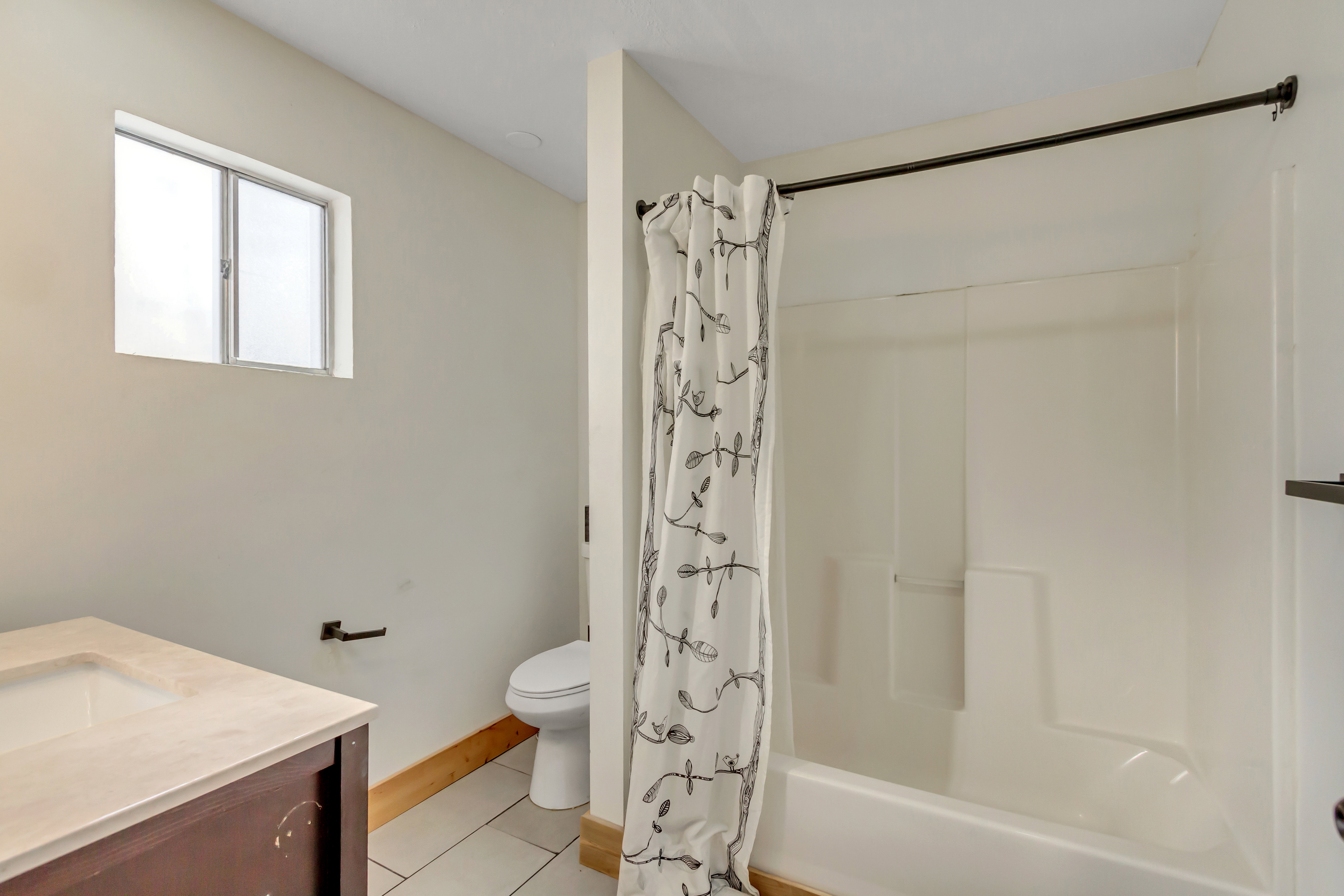 Full bathroom with vanity, light tile patterned floors, and shower / bath combo with shower curtain