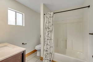 Full bathroom with vanity, light tile patterned floors, and shower / bath combo with shower curtain
