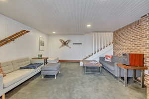 Living area featuring stairs, brick wall, and recessed lighting