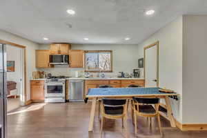 Kitchen featuring stainless steel appliances, light countertops, dark wood-style floors, recessed lighting, and light brown cabinets