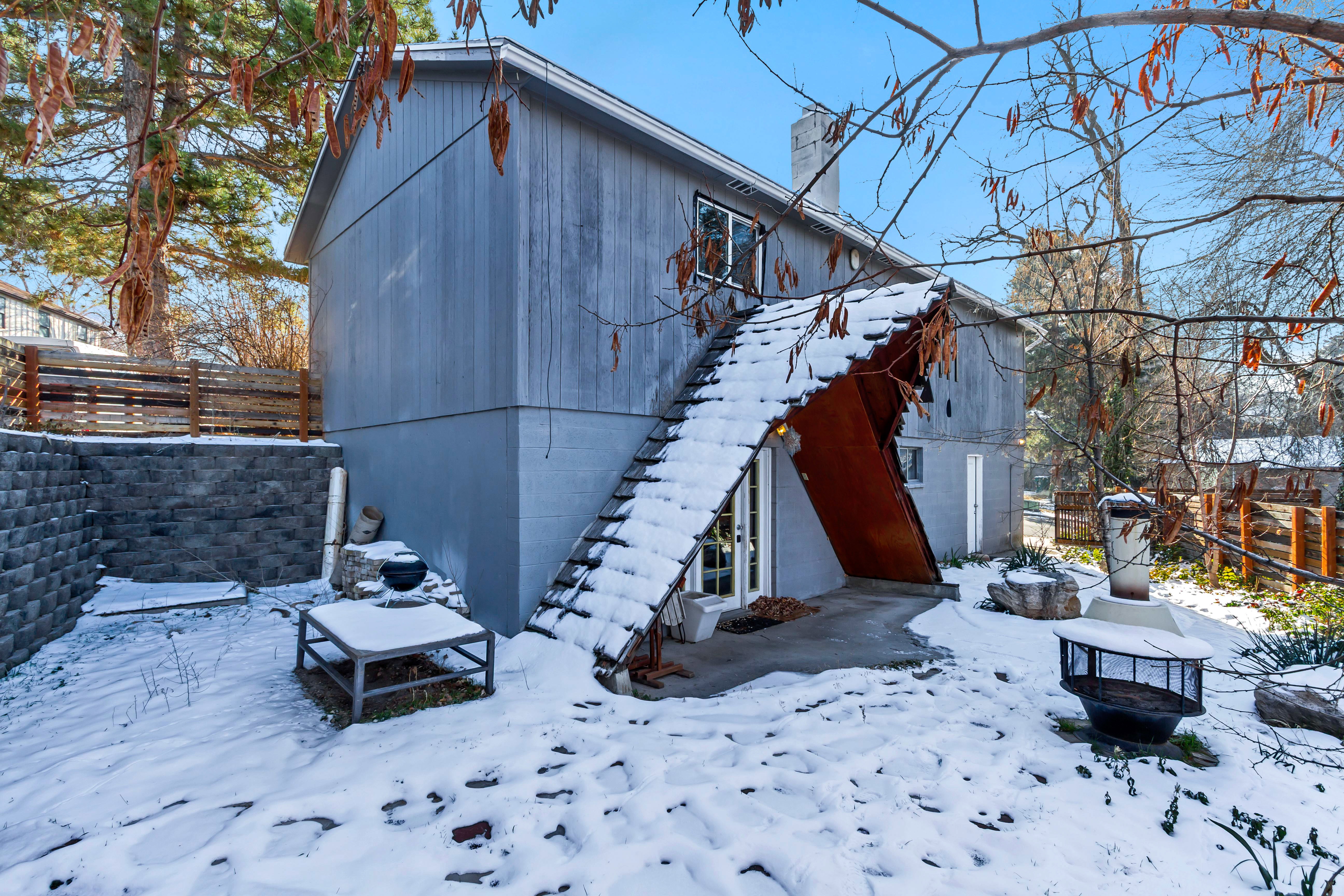 View of snow covered exterior featuring a patio area, stairs, and a chimney