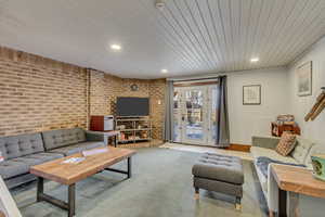 Living room with brick wall, wood ceiling, and recessed lighting