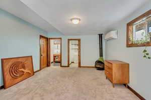 Bedroom featuring a spacious closet, light colored carpet, and a wall unit AC