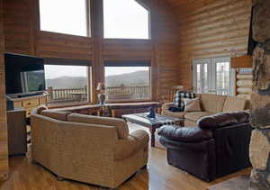 Living area with a high ceiling, wood finished floors, log walls, french doors, and a mountain view