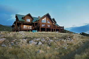 Rear view of house featuring a chimney, a deck, a metal roof, and log exterior