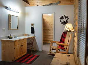 Bathroom with dark colored carpet and vanity