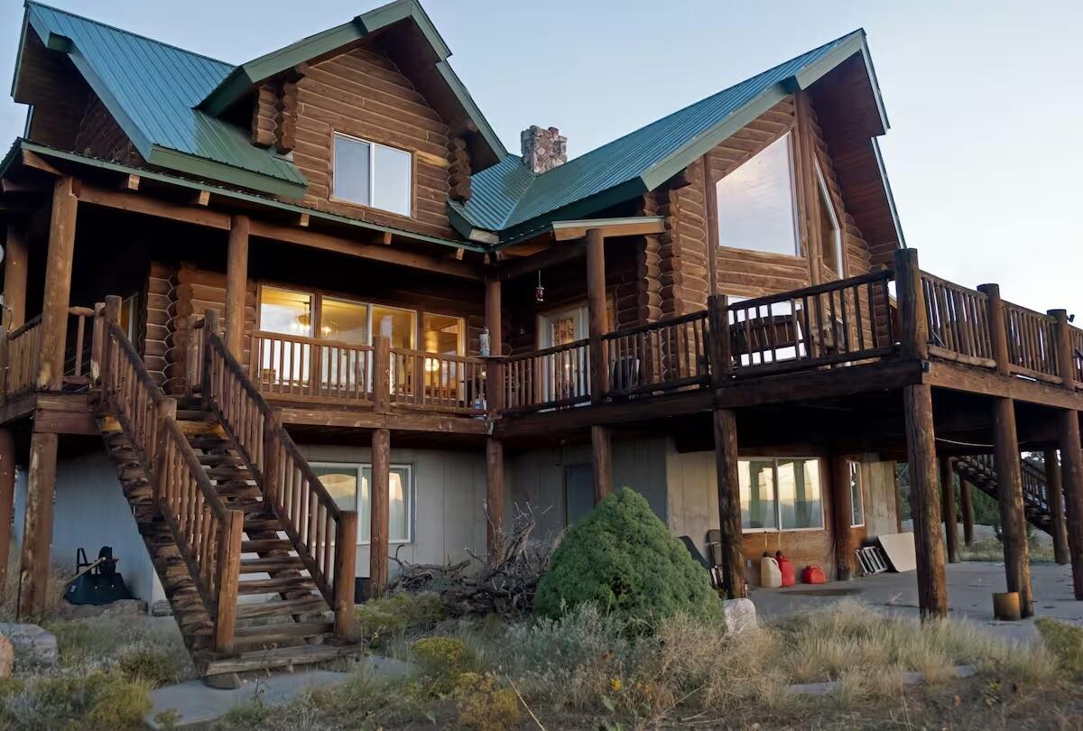Back of house with log exterior, stairs, a metal roof, and a chimney