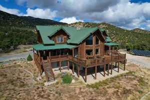 Back of house featuring log exterior, a metal roof, solar panels, and stairs