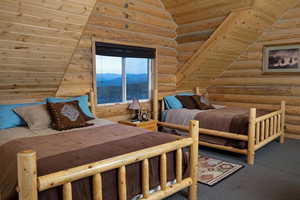 Bedroom featuring wood ceiling, vaulted ceiling, log walls, and carpet