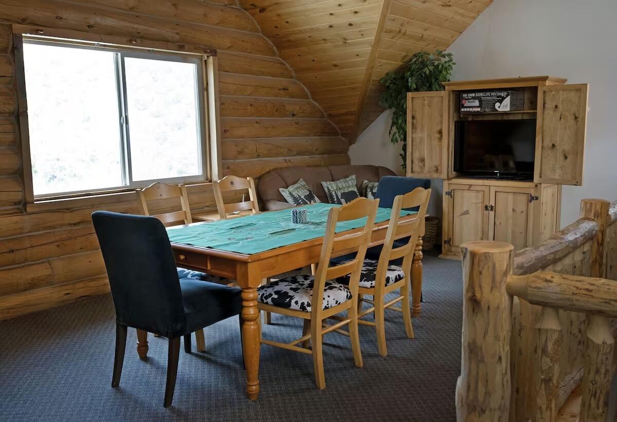 Carpeted dining room featuring wooden ceiling, vaulted ceiling, and rustic walls