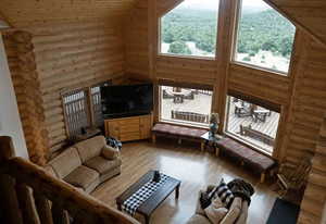Living room with log walls, high vaulted ceiling, wood finished floors, and wooden ceiling