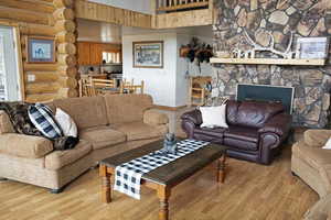Living room featuring rustic walls, a fireplace, light wood-style flooring, and a high ceiling