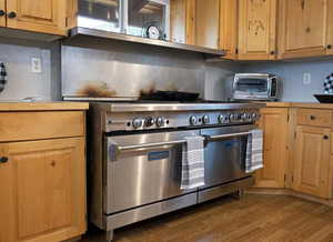 Kitchen featuring range with two ovens, dark wood-style floors, light countertops, and backsplash