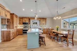 Kitchen featuring lofted ceiling, pendant lighting, a kitchen island, stainless steel appliances, and backsplash