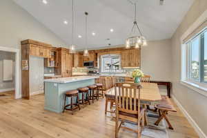 Dining room with light wood finished floors, a chandelier, high vaulted ceiling, and recessed lighting
