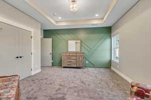 Primary bedroom featuring a tray ceiling.