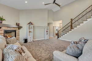 Living area with a fireplace, high vaulted ceiling, stairs, carpet floors, and a barn door