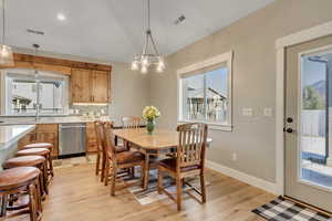 Dining space with healthy amount of natural light, vaulted ceiling, light wood-style floors, a chandelier, and recessed lighting