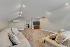 Carpeted family room with vaulted ceiling, recessed lighting, and an AC wall unit
