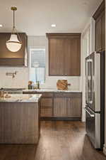Kitchen featuring high end refrigerator, dark wood-style flooring, custom exhaust hood, backsplash, and a textured ceiling