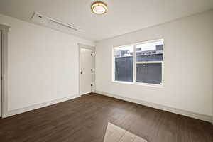 Unfurnished room featuring dark wood-style flooring and baseboards