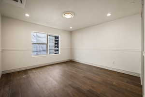 Spare room featuring a textured ceiling, dark wood-type flooring, and recessed lighting