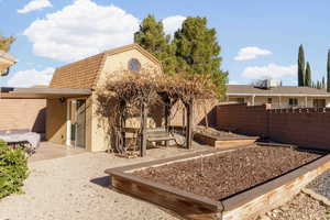 Back of property featuring a garden, stucco siding, and a shingled roof