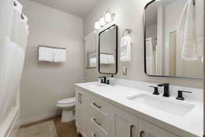 Full bath featuring double vanity, dark tile patterned floors, and shower / tub combo