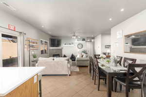 Dining space with a ceiling fan, recessed lighting, a stone fireplace, and light tile patterned flooring