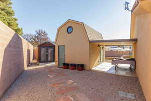 View of home's exterior featuring a fenced backyard, an outbuilding, stucco siding, and a gambrel roof