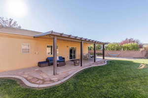 Rear view of property featuring outdoor lounge area, a patio, and stucco siding