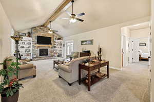 Living area with light carpet, a fireplace, built in features, and ceiling fan