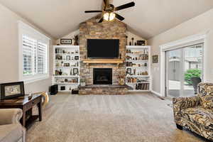 Living room featuring light carpet, a fireplace, a ceiling fan, and lofted ceiling