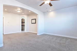 Empty room with light carpet, recessed lighting, a ceiling fan, and arched walkways