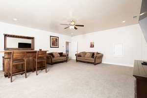 Living area with recessed lighting, light carpet, and a ceiling fan
