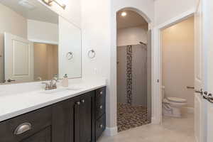 Bathroom featuring a walk in shower, vanity, and light tile patterned floors