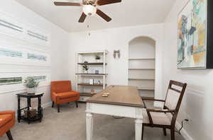 Home office with light carpet and a ceiling fan